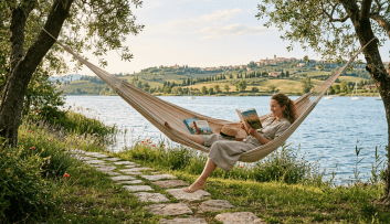 Woman reading a book in a hammock beside a lake with hills in the background
